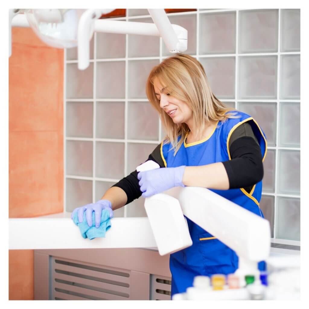 woman wearing gloves sprays cleaner in a dental office 