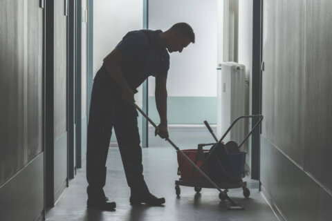 person uses a mop bucket while cleaning a floor