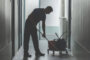 person uses a mop bucket while cleaning a floor