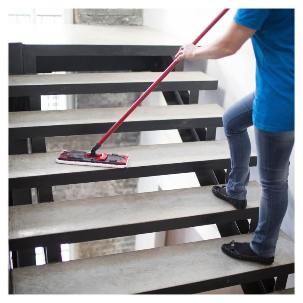 person mops large stairs in a business 