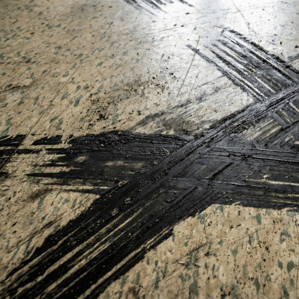 black rubber scuff marks on a worn hospital linoleum floor