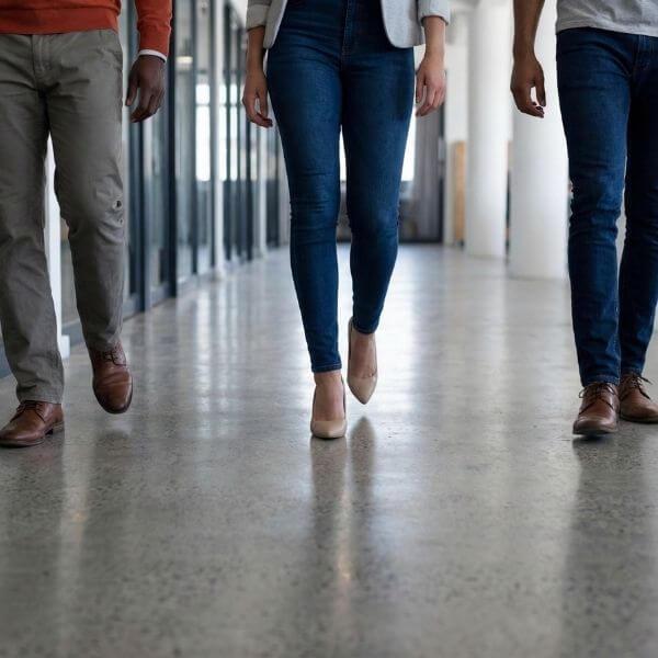 People walking down a modern office hallway showing foot traffic on polished concrete flooring.