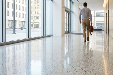 A wide view of a brightly lit modern office lobby with highly polished reflective floors.
