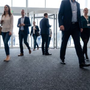 Low angle view of business people walking across a large entryway carpet in a corporate lobby.