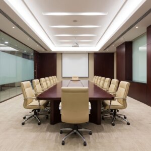 An empty, modern corporate boardroom with a large table and clean, light beige carpeting.