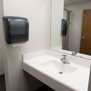 A brightly lit and fresh-looking office restroom featuring a gleaming clean white sink and faucet.